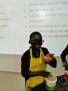 A young man wearing an apron and glasses.