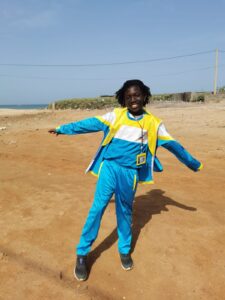 A man in blue and yellow outfit standing on dirt.