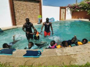 A group of people in the pool with water toys.
