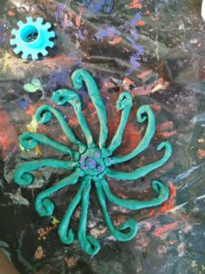 A green flower with blue center and purple gears.