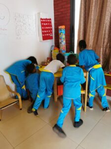A group of children in blue uniforms sitting at a table.