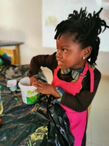A little girl sitting at the table with a cup.