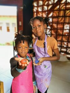 Two young girls holding apples and wearing aprons.