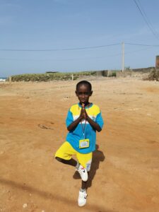 A young boy kneeling down in the sand.