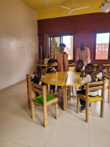 A group of children sitting at a table in a classroom.