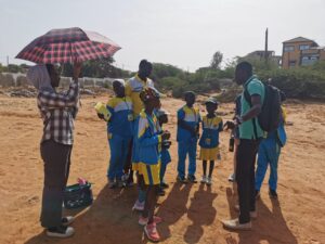A group of people standing on top of a dirt field.
