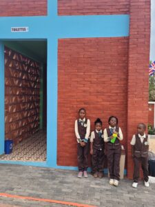 Four children standing in front of a brick wall.