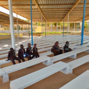 A group of people sitting on top of white benches.