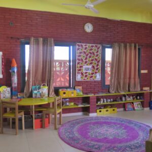 A room with tables and chairs, a rug and windows.