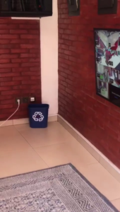 A blue trash can sitting in the corner of a room.