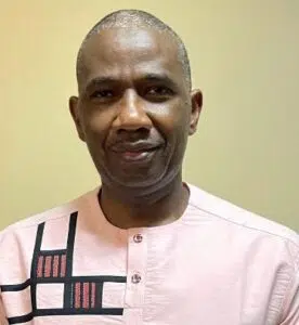 A man with gray hair and an african print shirt.